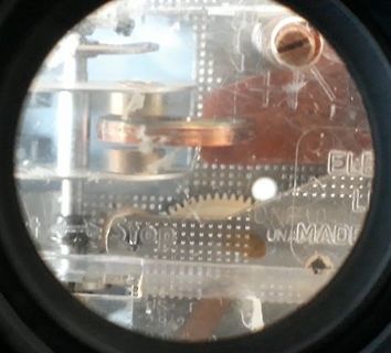 Nahaufnahme eines mechanischen Uhrwerks durch ein Glas