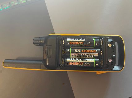 Batteriefach eines gelben Geräts mit drei Batterien
