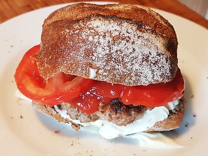 Burger mit Tomate und Sauce auf weißem Teller