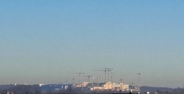 Landschaft mit Gebäuden und Strommasten unter blauem Himmel