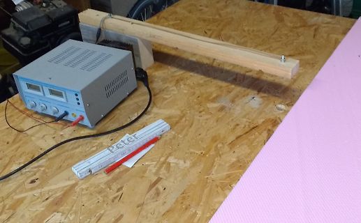 Laboraufbau mit Netzteil und Hebelarm auf Holzbrett