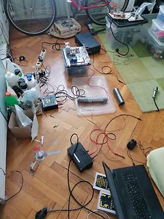 Elektronik-Versuchsaufbau auf Holzboden mit Laptop und Messgeräten