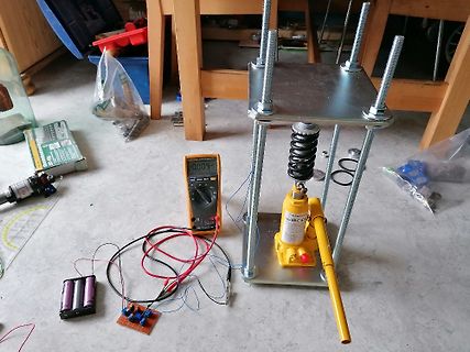 Elektronik-Aufbau mit Multimeter, Batterie und Wagenheber