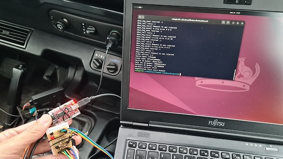 Laptop mit Fehlermeldungen und Mikrocontroller-Aufbau im Auto