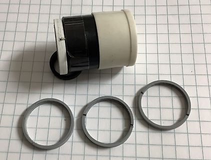 Druckknopf und drei O-Ringe auf Millimeterpapier