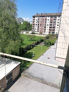 Blick von einem Balkon auf einen Garten und ein Wohngebäude