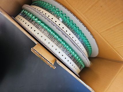 Zwei Rollen mit grünen SMD-Bauteilen in einem Karton