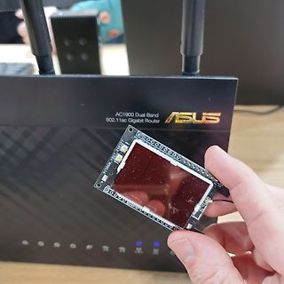 Hand hält kleine Platine vor ASUS Router