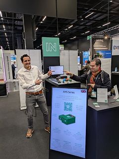 Männer an einem Messgeräte-Stand auf einer Messe