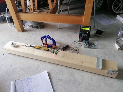 Elektronischer Versuchsaufbau auf Holzbrett mit Multimeter