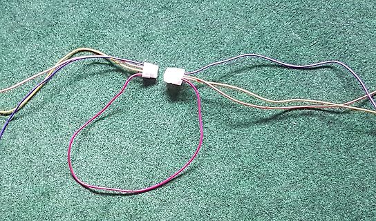 Bunte Kabel mit weißen Steckverbindern auf grünem Untergrund