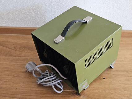 Grünes Metallgehäuse mit Tragegriff und Netzkabel