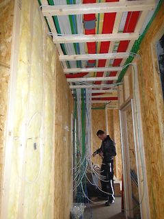 Person verlegt Kabel in Rohren an einer Decke