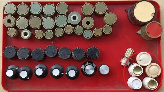 Vielzahl verschiedener Drehregler und Potentiometer auf rotem Tablett