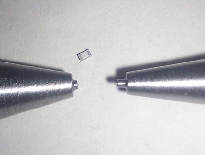Mikroskopische Aufnahme eines kleinen Bauteils zwischen zwei Spitzen