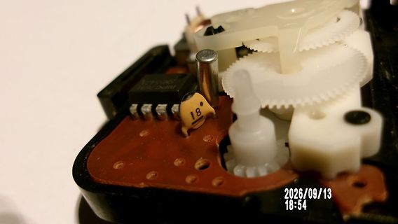 Innenansicht eines mechanischen Bauteils mit Zahnrädern und Platine