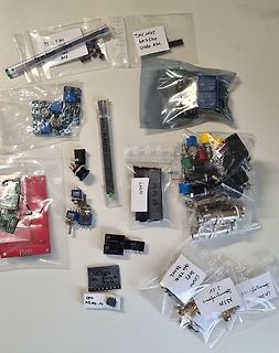 Verschiedene Elektronikbauteile in Plastikbeuteln auf weißem Untergrund