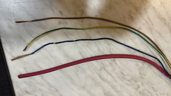 Vier verschiedene isolierte Kabel auf einer Oberfläche