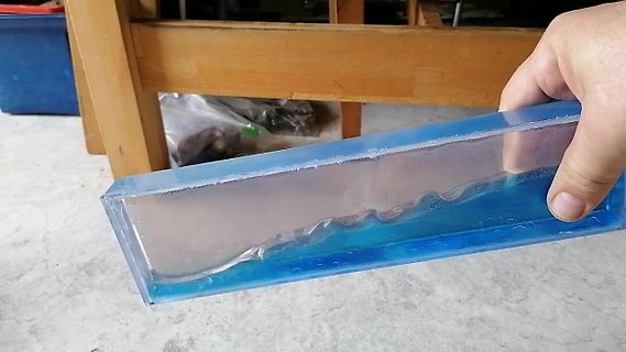 Hand hält einen blauen Kunststoffblock