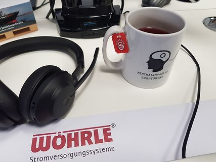 Headset, Tasse und Werbematerial auf einem Tisch