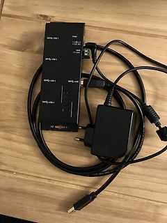 USB-Hub mit Netzteil und Kabeln auf Holztisch