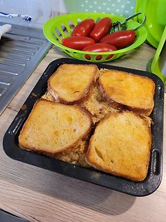Toastbrot in einer Auflaufform mit Tomaten im Hintergrund