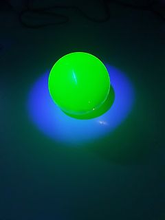 Leuchtende grüne Kugel auf blauem Untergrund