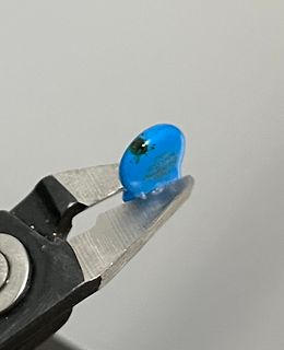 Blaues Bauteil in einer Zange