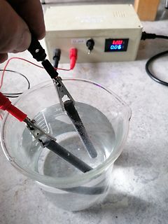 Elektrolyseversuch mit Netzteil und Becherglas
