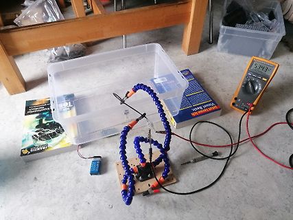 Elektrischer Versuchsaufbau mit Multimeter und Batterie
