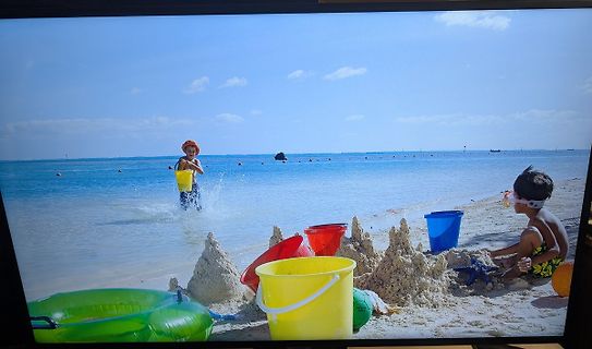 Kinder spielen am Strand mit Eimern und Sandburgen