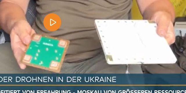 Person hält zwei Leiterplatten vor einem Hintergrund