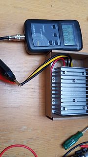 Multimeter, DC-DC-Wandler und Messkabel auf Holztisch