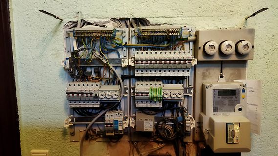 Unordentlicher Elektroverteiler mit Sicherungsautomaten und Leitungen