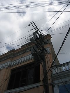 Stromleitungen und Strommast vor einem Gebäude