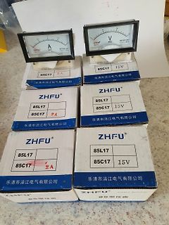 Mehrere analoge Amperemeter und Voltmeter in Kartons