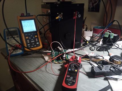Elektronik-Messaufbau mit Multimeter, Stromzange und Batterie