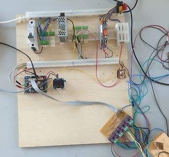 Elektronischer Versuchsaufbau auf Holzbrett mit Mikrocontroller und Netzteil