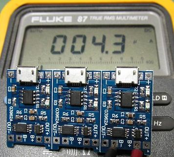 Drei kleine Leiterplatten vor einem Multimeter