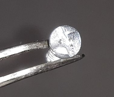 Kleines metallisches Bauteil in einer Pinzette