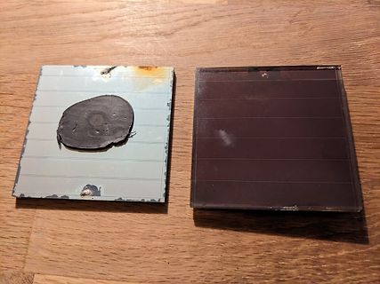 Zwei beschädigte Solarzellen auf Holzuntergrund