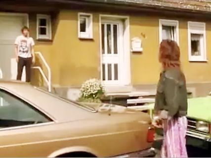 Personen vor einem Haus und einem Auto