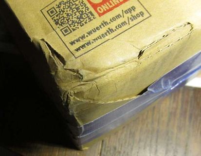 Beschädigter Karton mit QR-Code und Webadresse