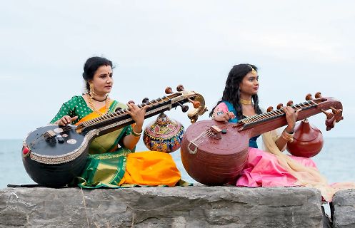 Zwei Frauen spielen traditionelle indische Saiteninstrumente am Strand