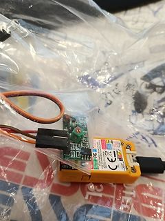Elektronikbauteile und gelbes Gehäuse auf Plastikfolie
