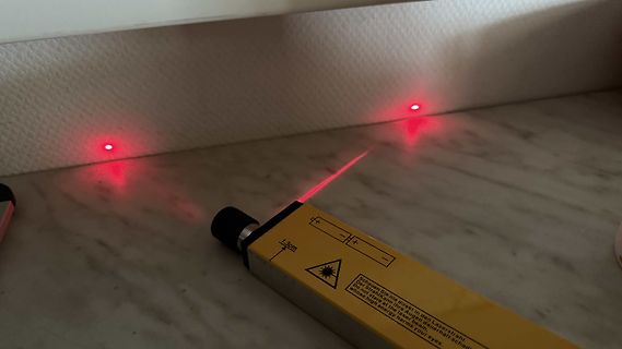 Laserpointer mit zwei roten Lichtpunkten auf Wand und Tisch