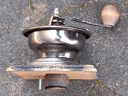 Kaffeemühle aus Metall auf Holzbrett