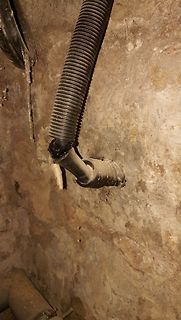 Schwarzes Wellrohr an einem Anschlussstück an einer Wand