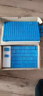 Blaue Bauteile in Kartons auf Holzboden