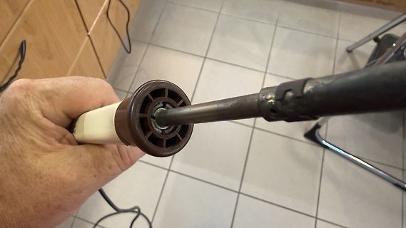 Hand hält eine Metallstange in einer Halterung